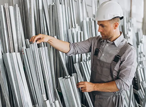 Worker inspecting aluminium profiles in warehouse
